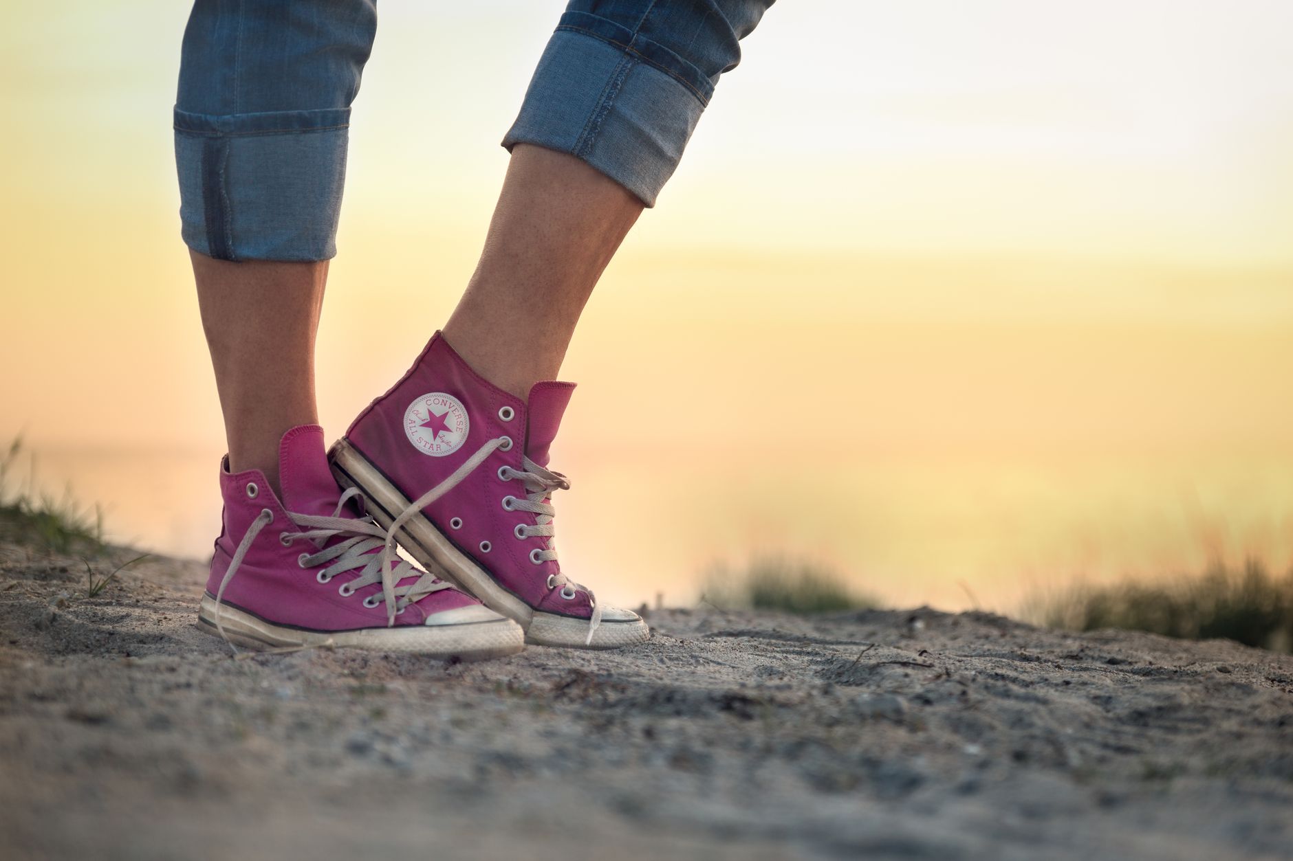 close up of woman wearing pink shoes and standing outdoors at sunset